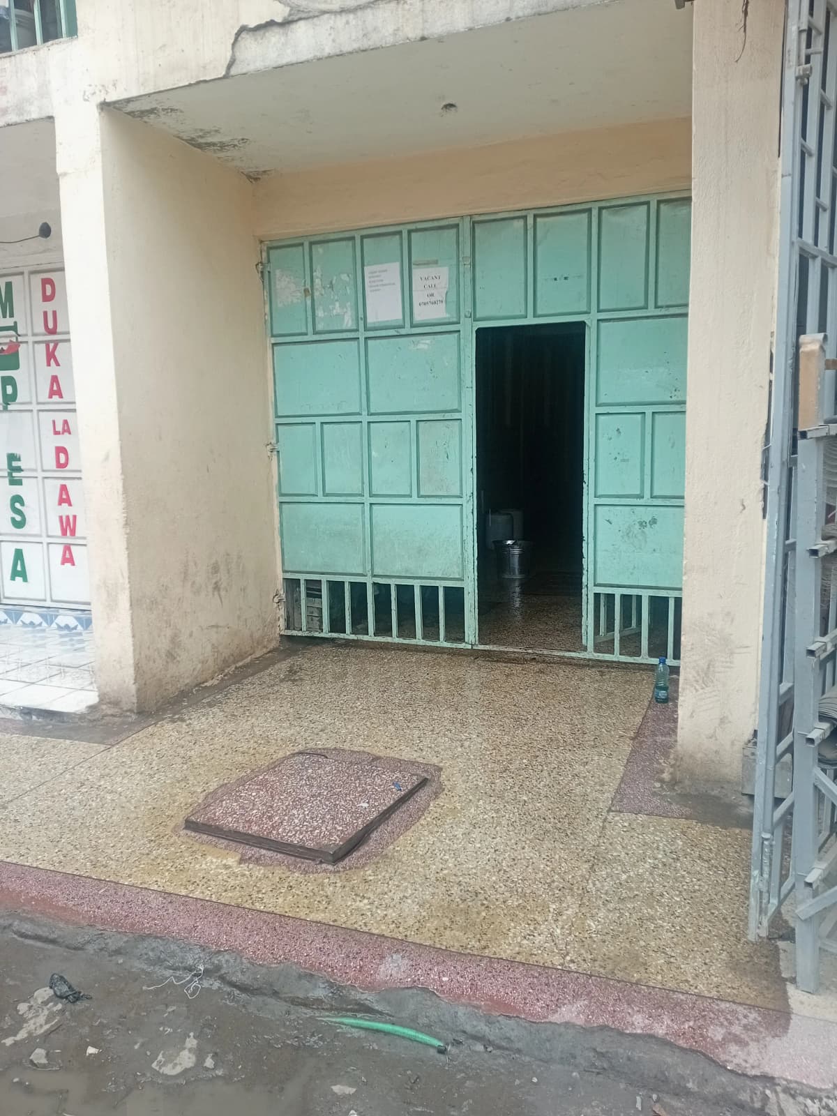 Ground floor entrance with green metal doors and compound gate