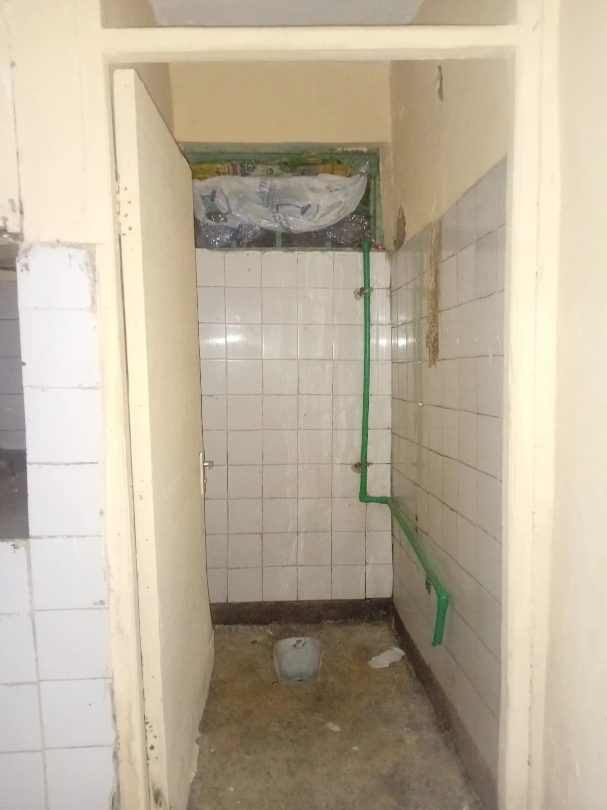 Basic bathroom with white tile walls, unfished plumbing setup