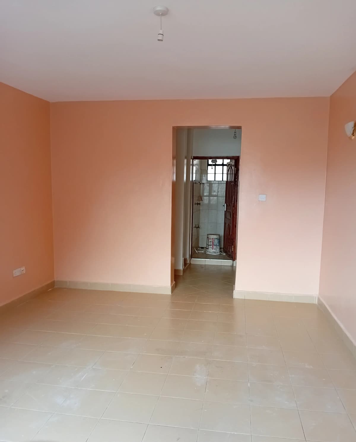 Empty living room with peach walls and tiled flooring