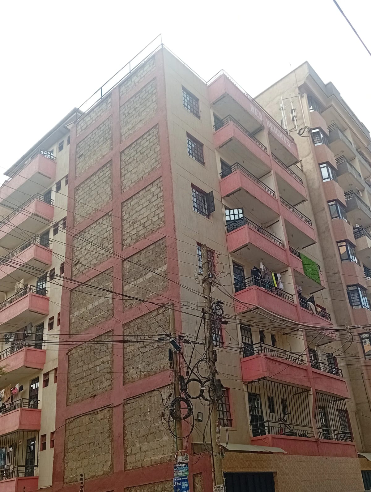Multi-story residential building facade with pink and stone finish