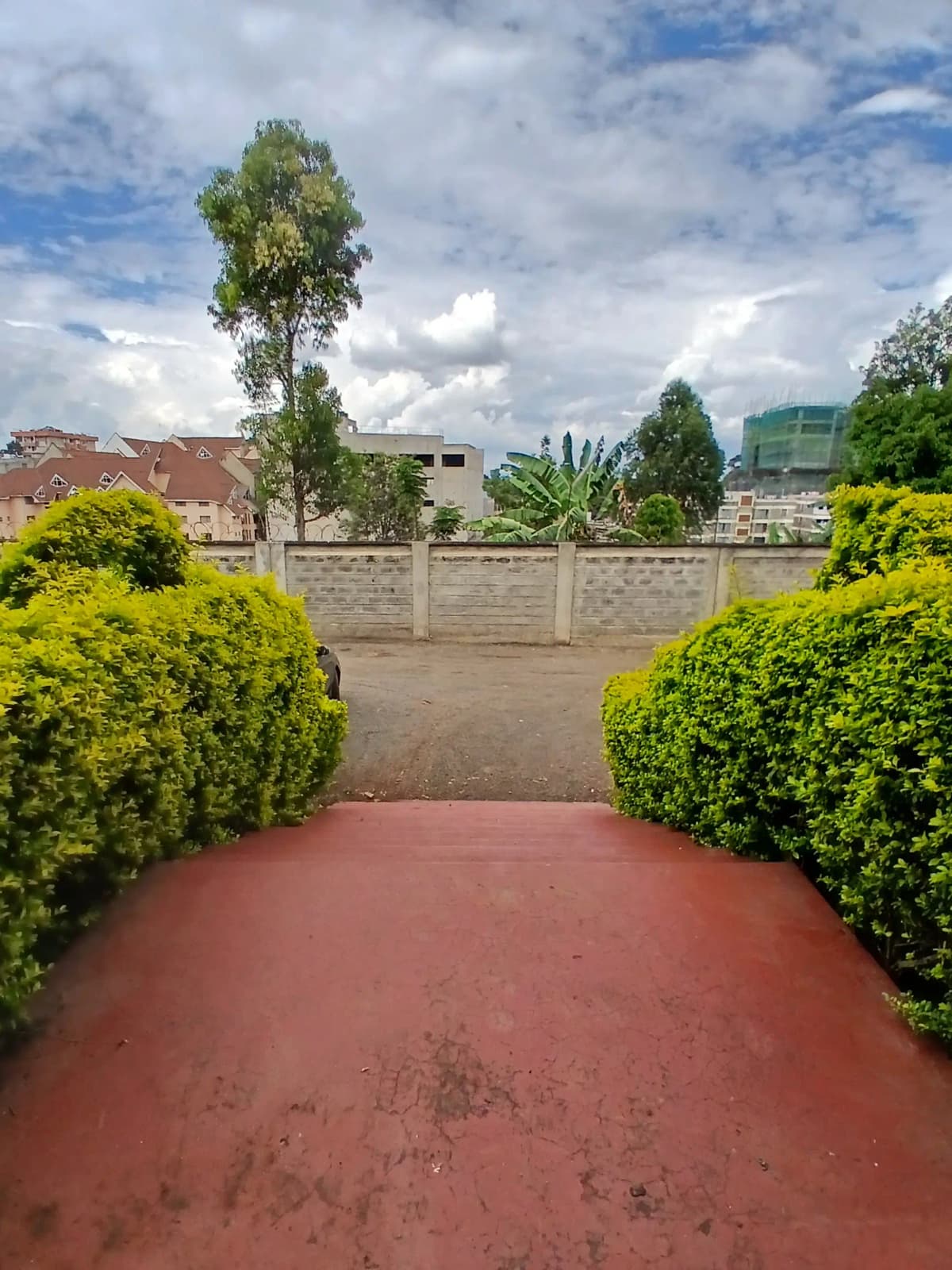 Compound driveway with manicured hedges and perimeter wall