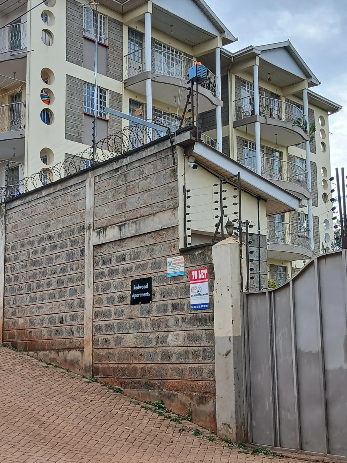 Multi-story residential building with compound wall and gate entrance