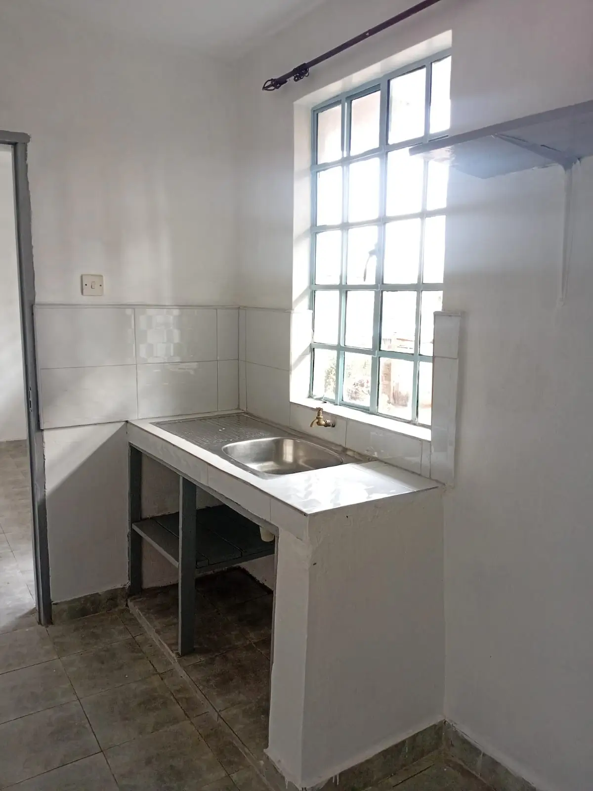 Compact kitchen with stainless steel sink and large window