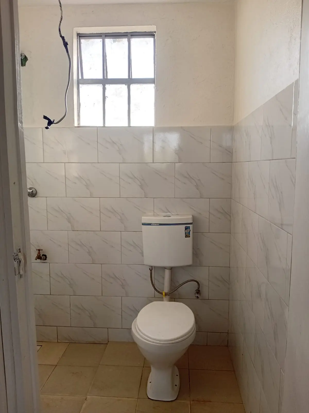 Simple bathroom with toilet, window, and marble tile walls