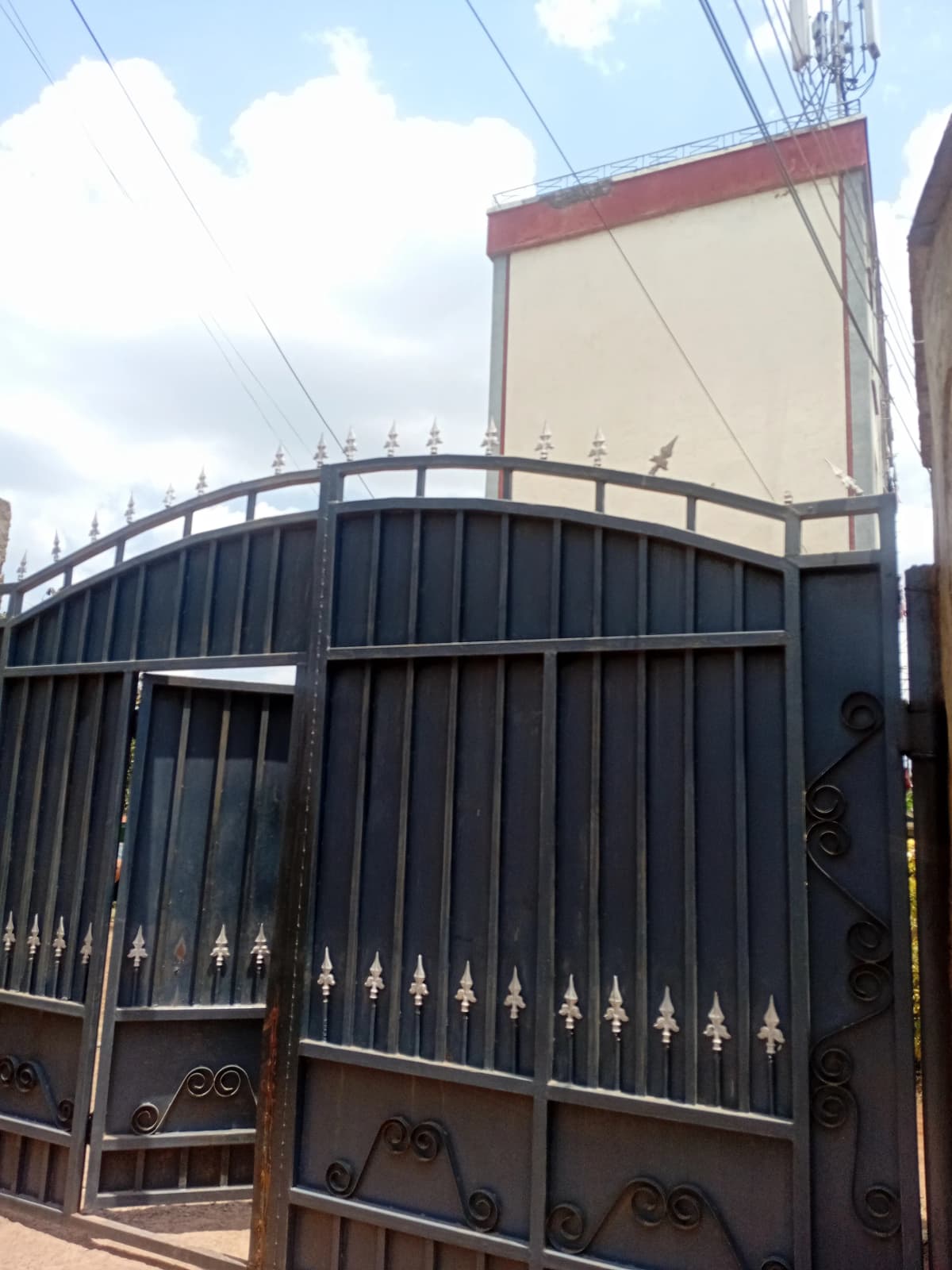 Dark metal gate entrance with cream and red building facade