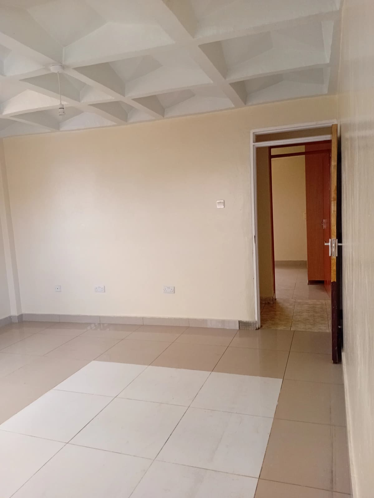 Spacious empty living room with coffered ceiling and tiled flooring