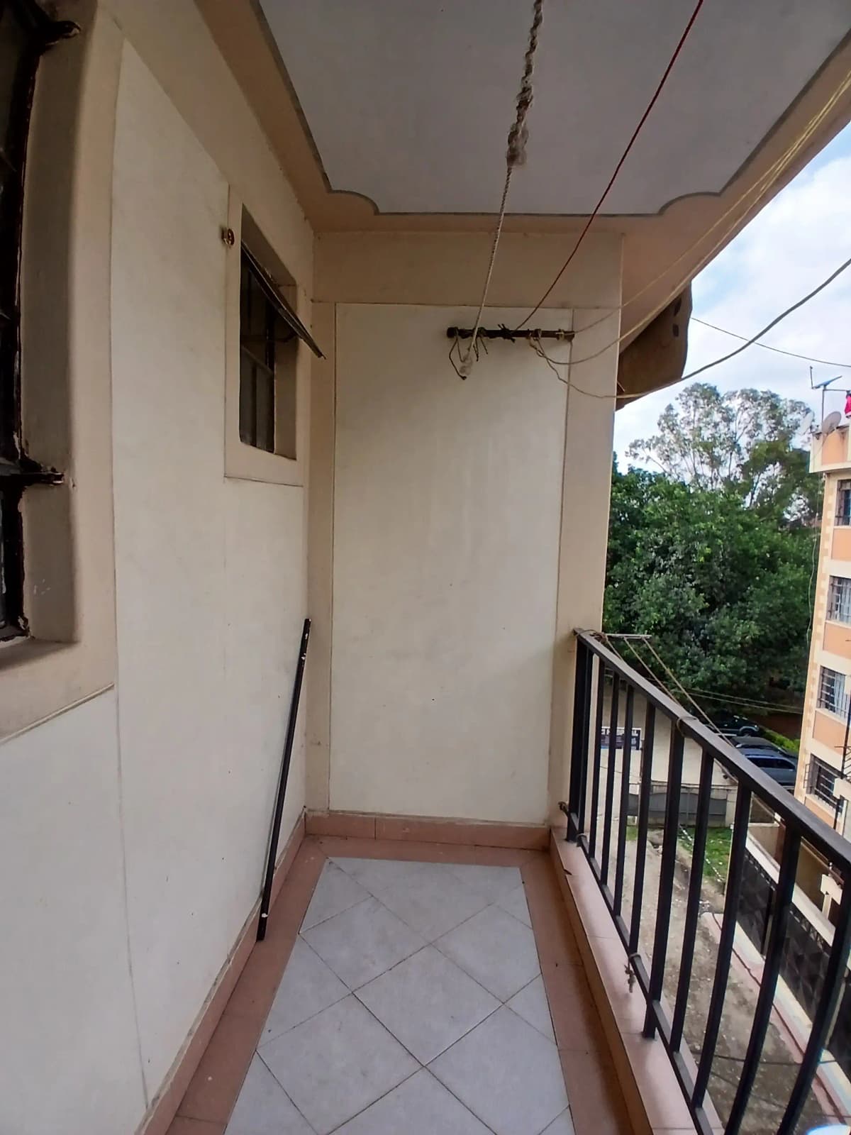 Narrow balcony with metal railing and tiled floor