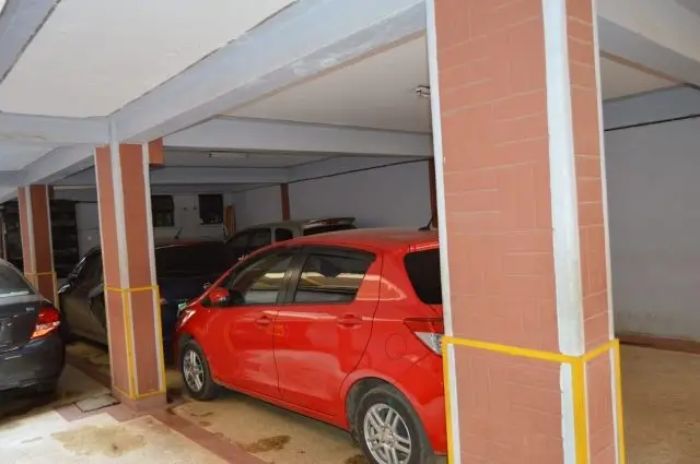 Covered basement parking with red vehicle and support columns