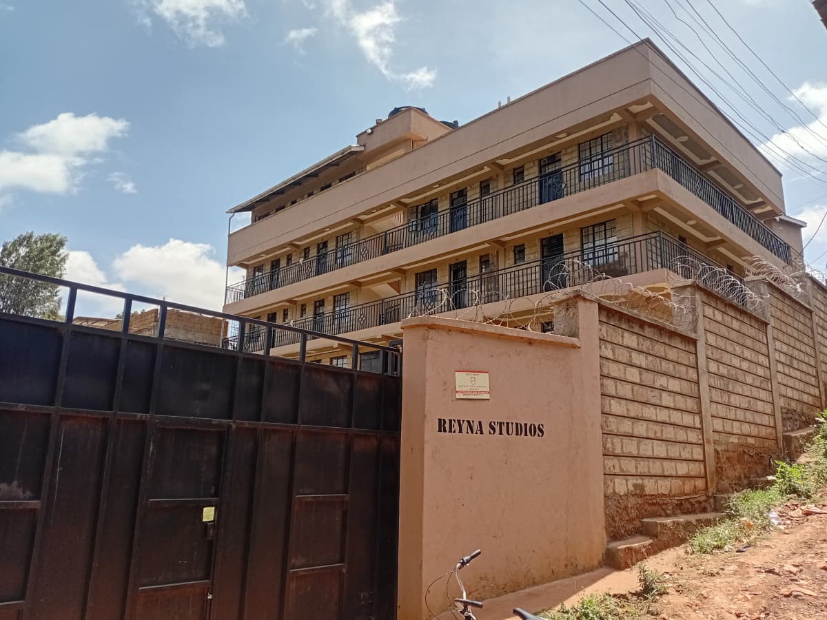 Multi-story residential building with metal gate and compound wall