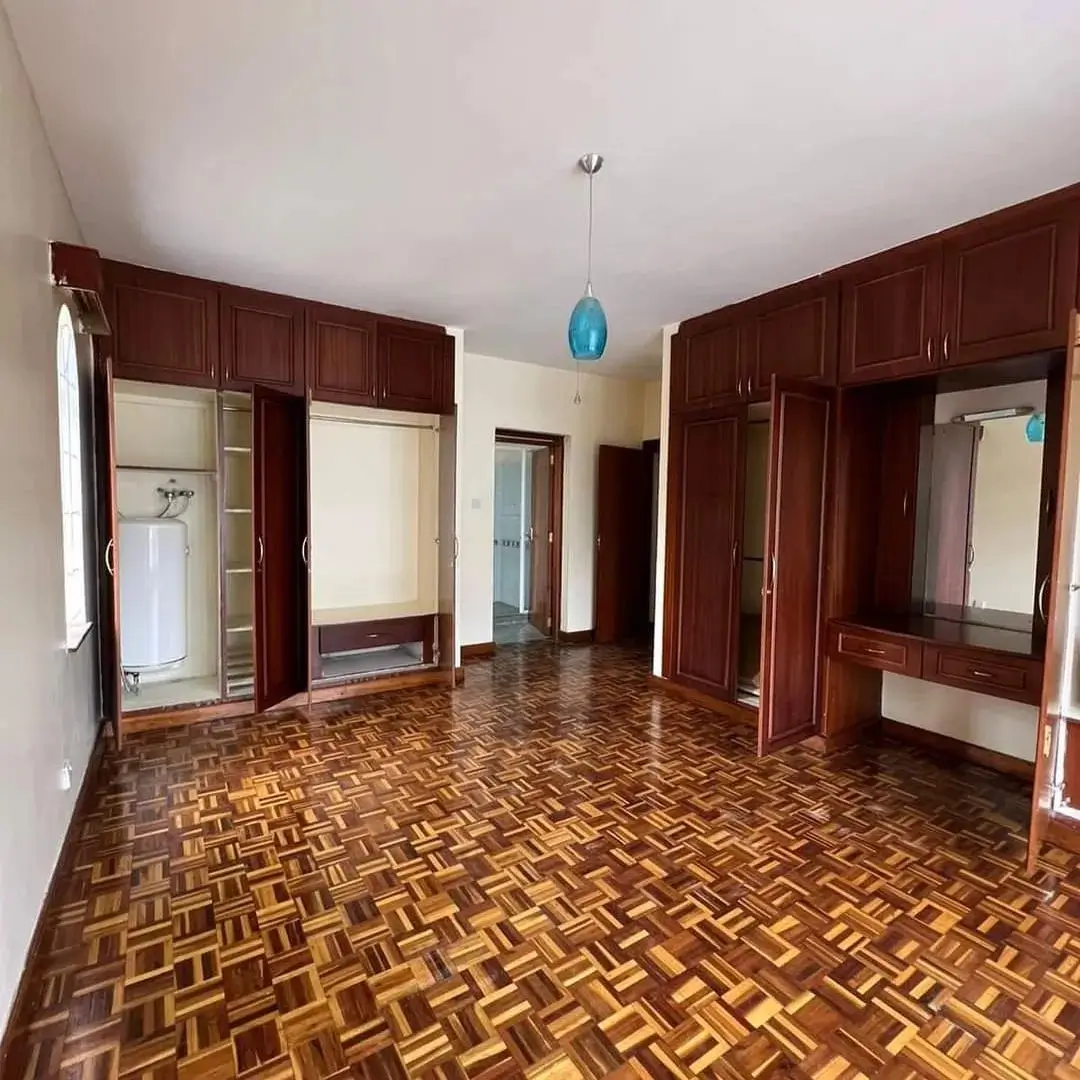 Spacious bedroom with built-in wooden wardrobes and herringbone flooring