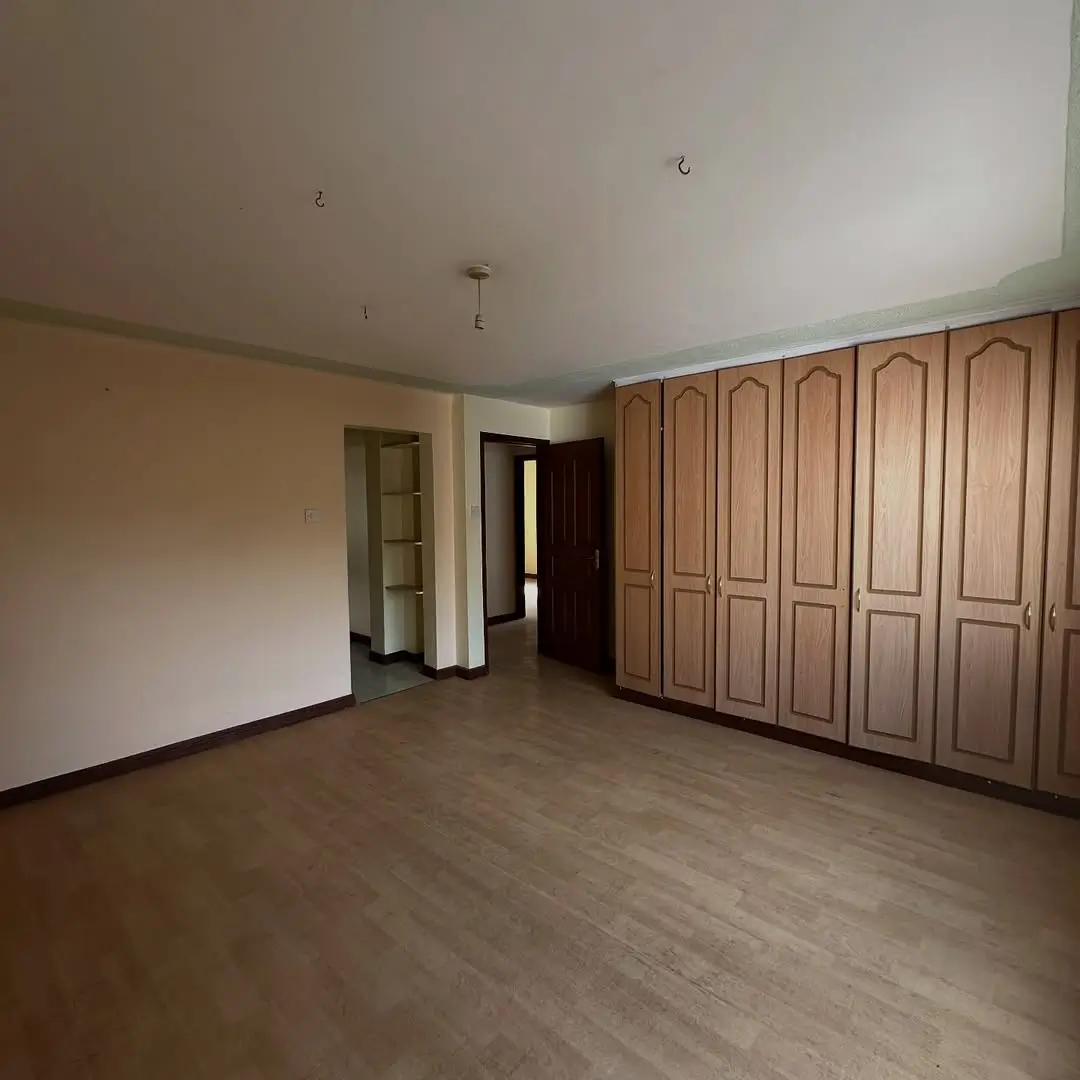 Spacious bedroom with wooden built-in wardrobes and wood flooring