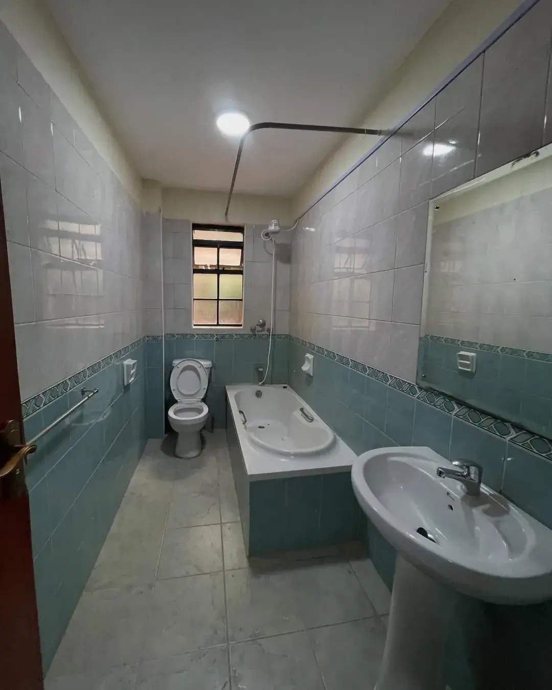 Spacious bathroom with dual sinks, toilet, and green tile accents