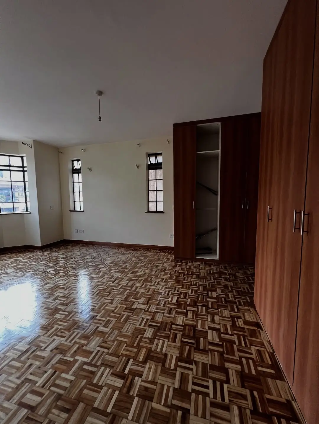 Spacious bedroom with built-in wooden wardrobe and parquet flooring
