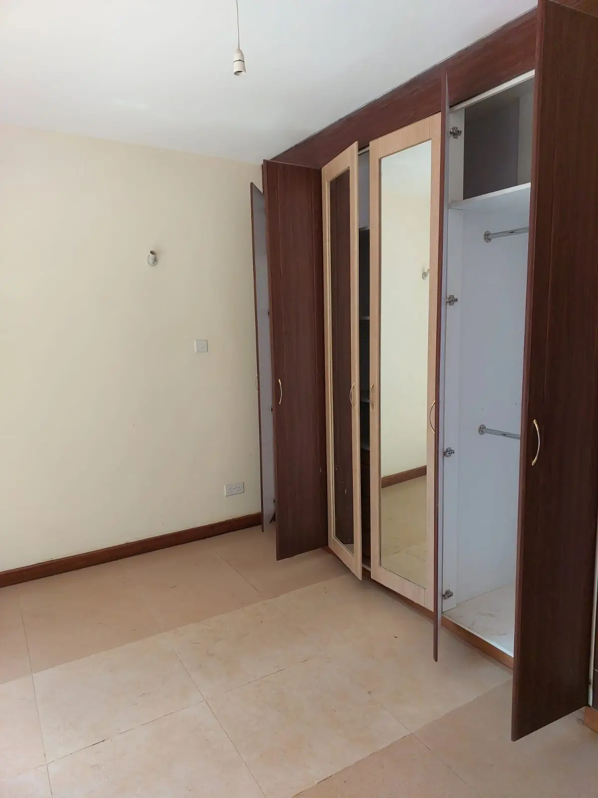 Spacious bedroom with built-in wooden wardrobe and mirror doors