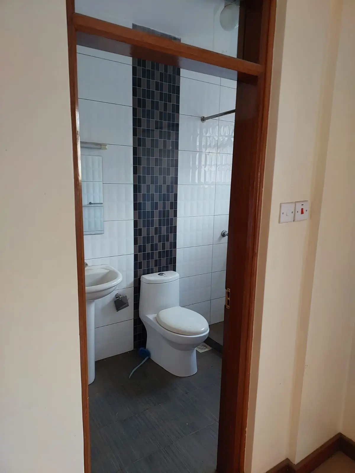 Compact bathroom with toilet, sink, and tiled shower enclosure