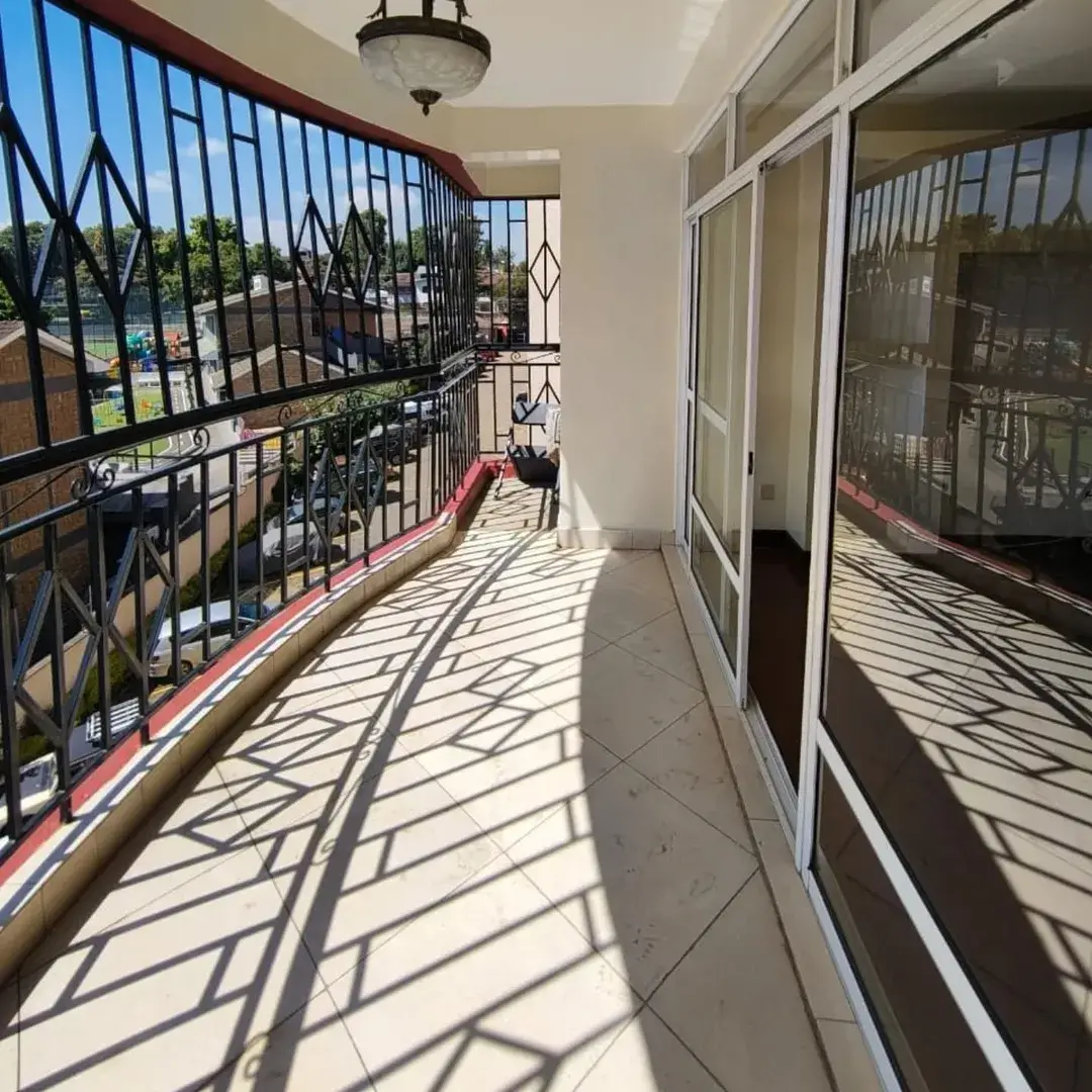 Spacious balcony with railing, overlooking green compound area
