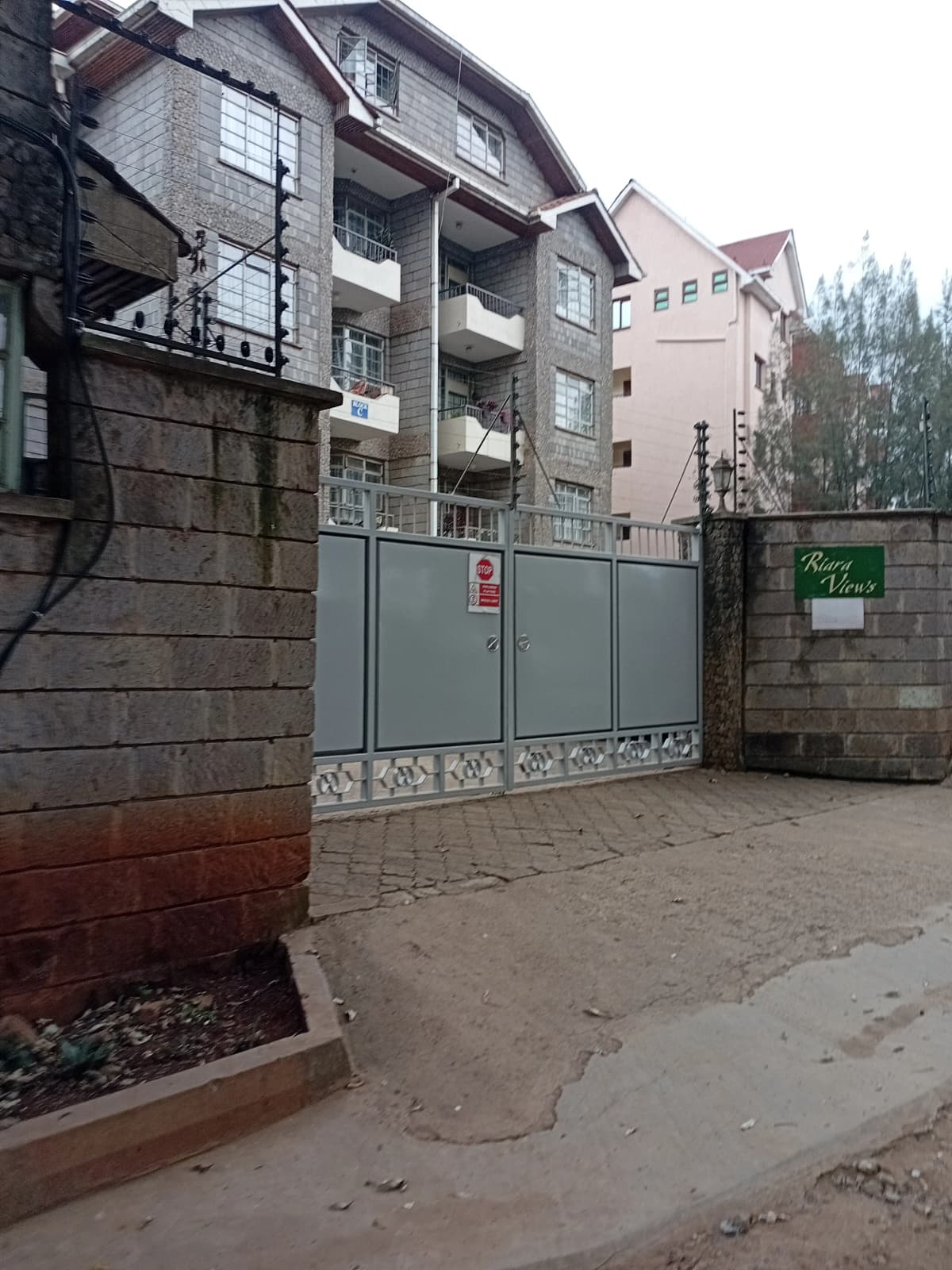 Secure gated compound entrance with multi-story residential building