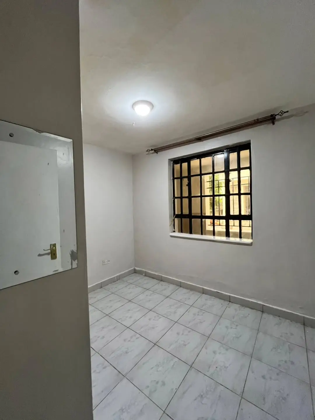 Sparse bedroom with barred window and tiled flooring