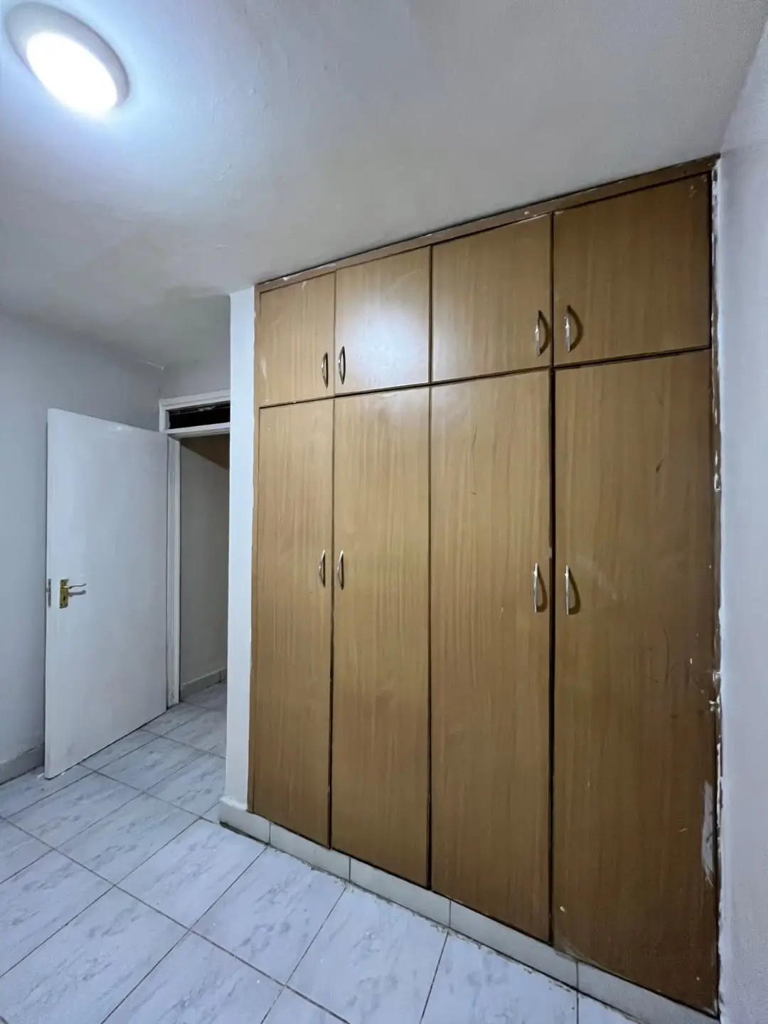 Bedroom with large wooden built-in wardrobe and tiled floor