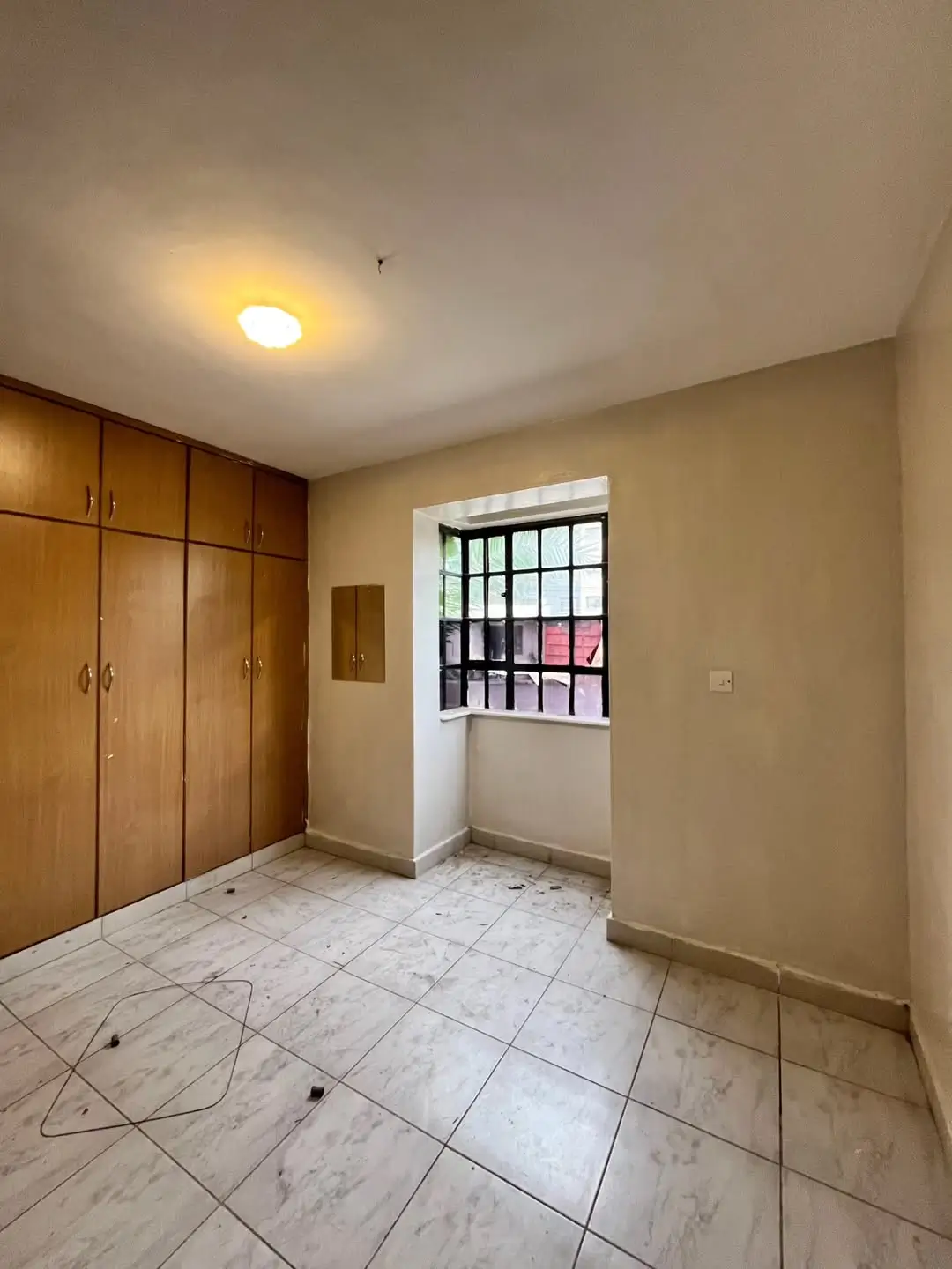 Spacious bedroom with wooden wardrobes and tiled flooring