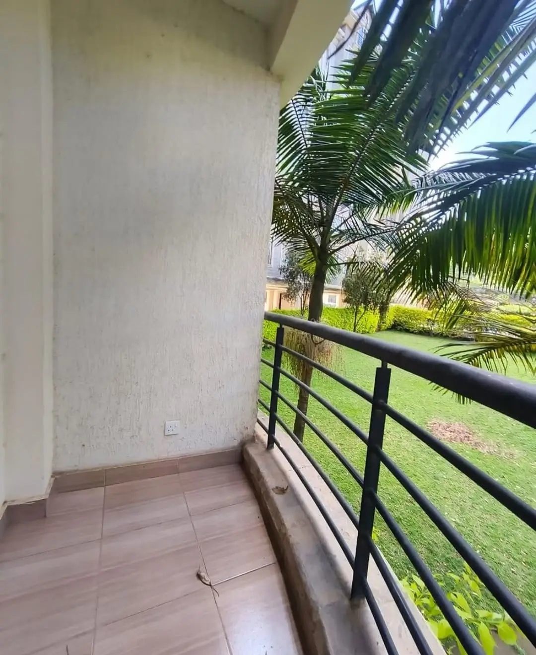 Spacious balcony overlooking manicured garden and palm trees