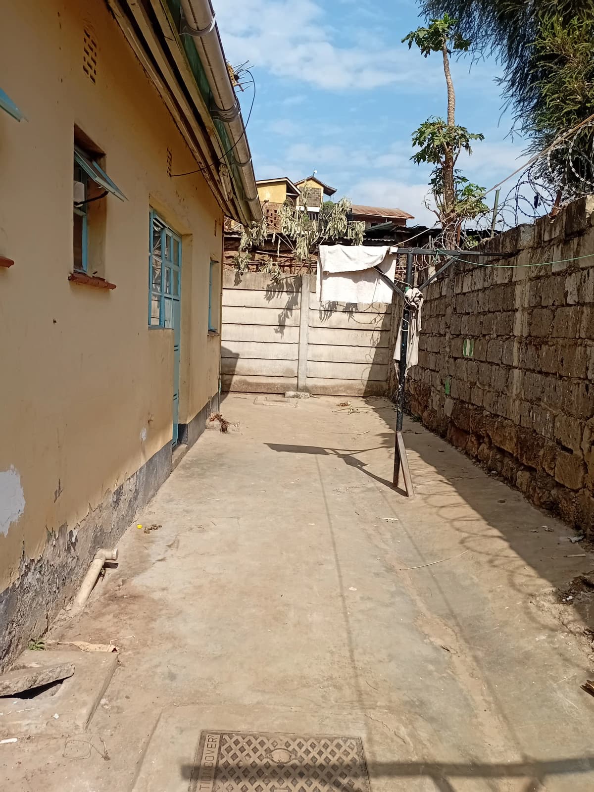 Compound driveway with yellow house wall and concrete gate