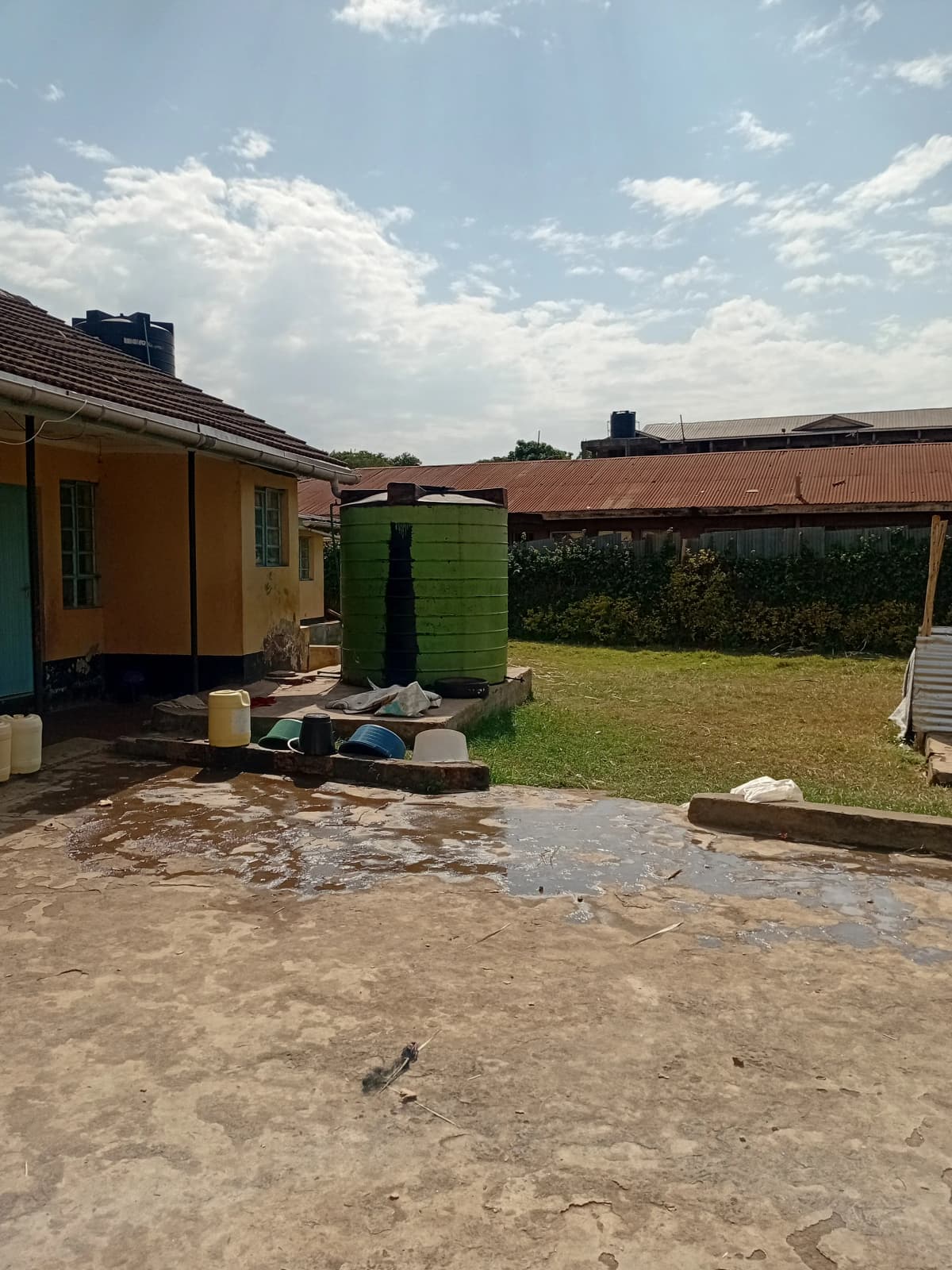 Compound grounds with yellow building, green water tank, lawn