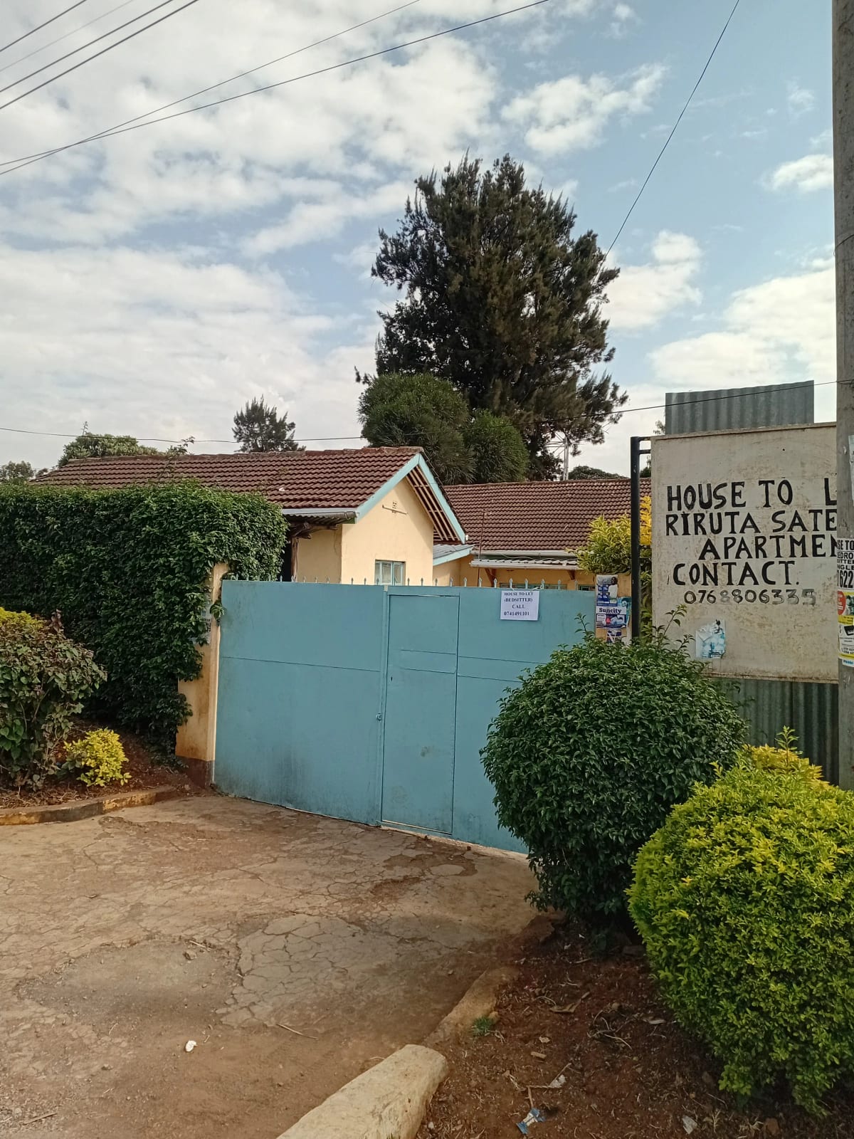 Property entrance with blue gate and manicured hedges