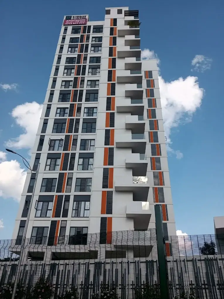 Modern multi-story residential building with balconies and metal fencing