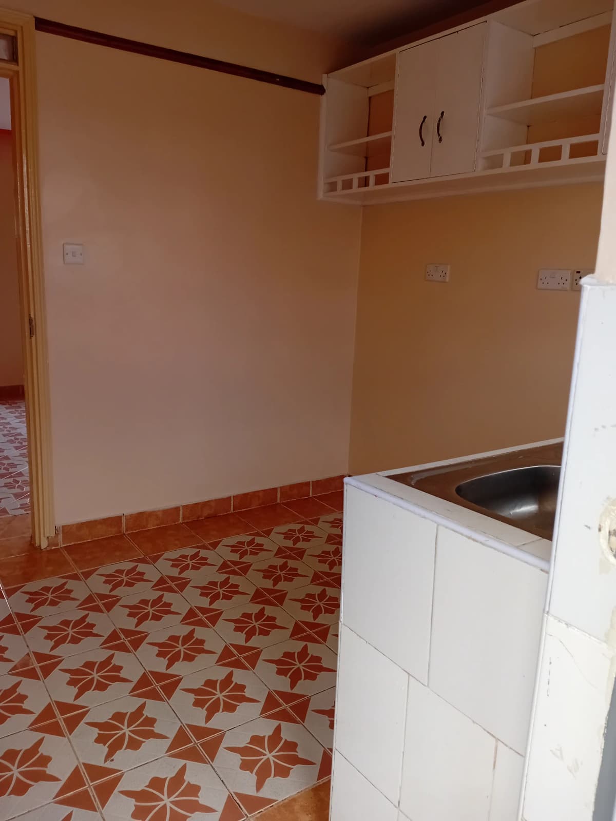 Compact kitchen with white cabinetry and geometric tile flooring