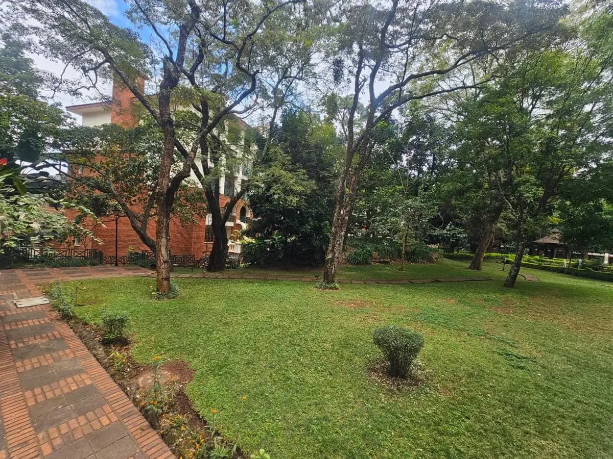 Spacious manicured garden with mature trees and brick pathway