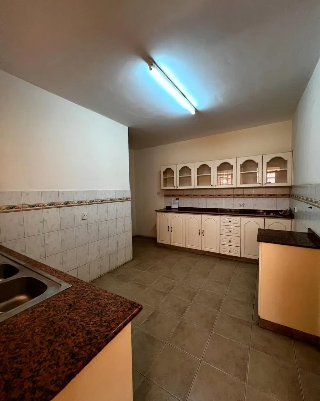Spacious kitchen with cream cabinets and tiled countertops