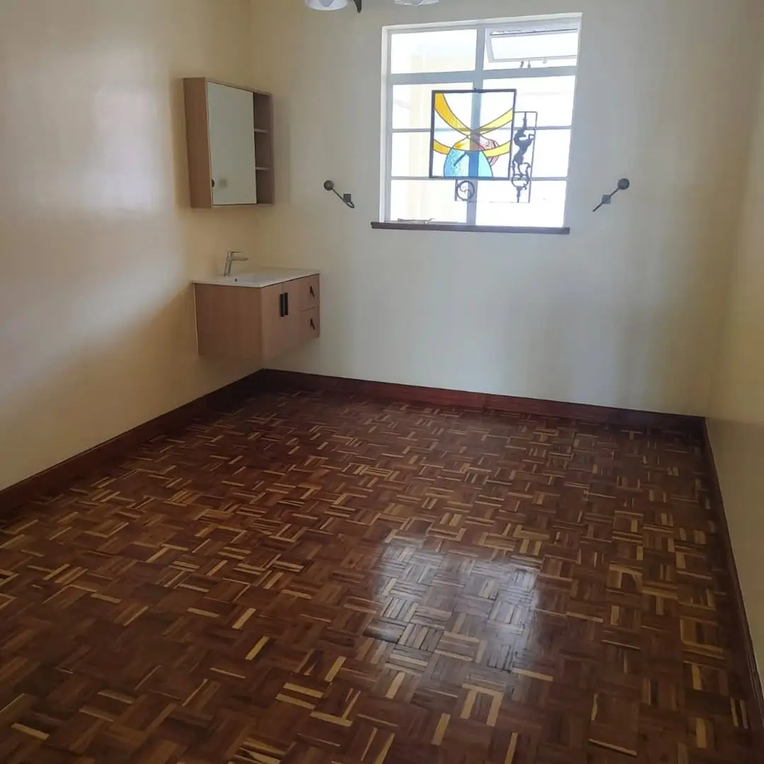 Spacious bedroom with wooden parquet flooring, bright window