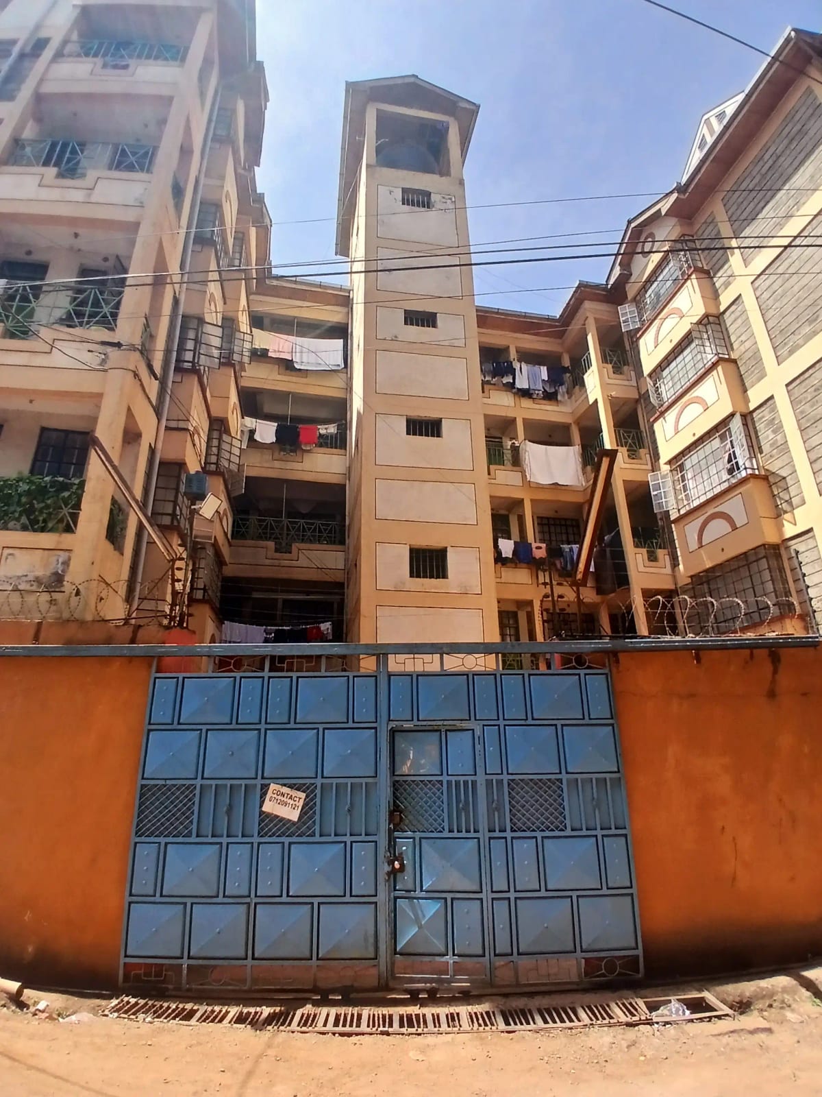 Multi-story residential building with blue metal gate entrance