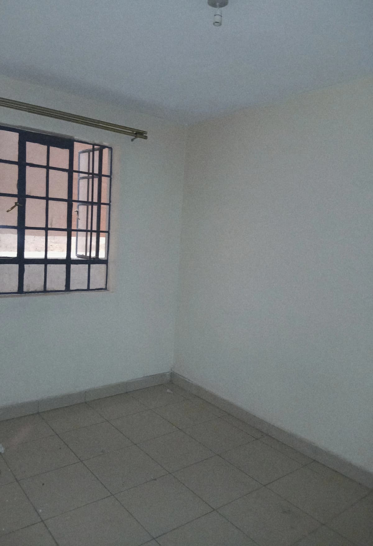 Empty bedroom with barred window and tiled flooring