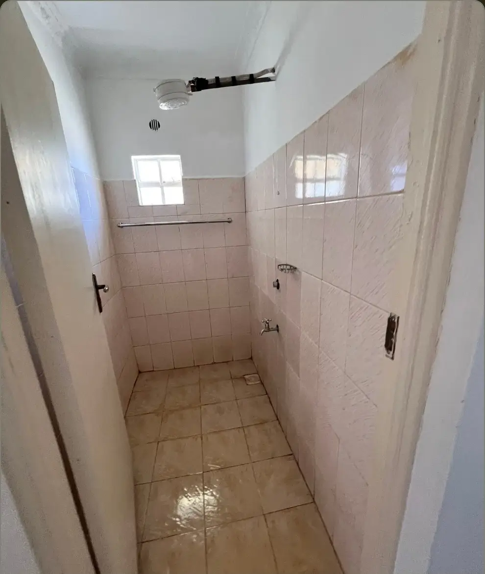 Narrow bathroom with beige tiles and shower area