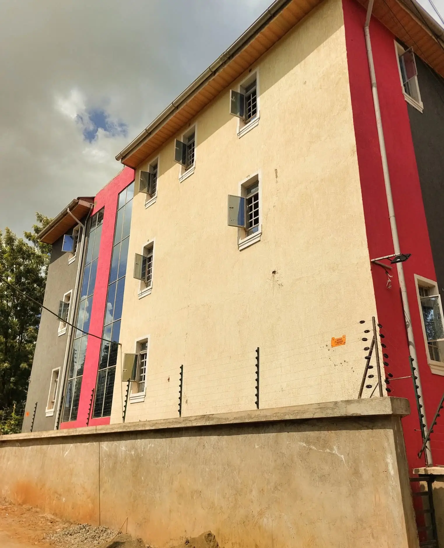 Multi-story residential building with cream facade and red trim
