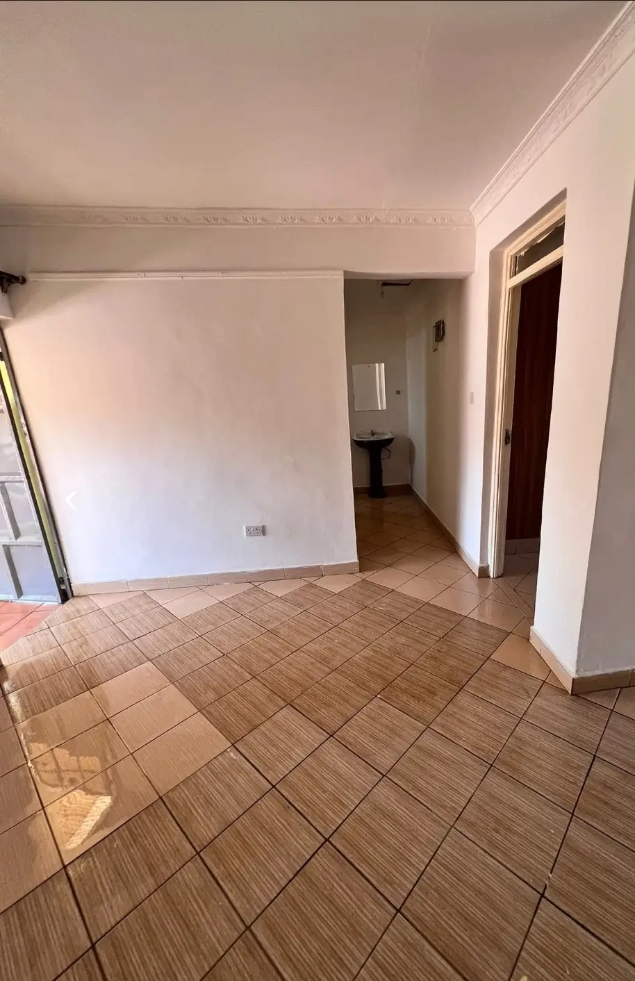 Spacious living room with terracotta tile flooring and white walls