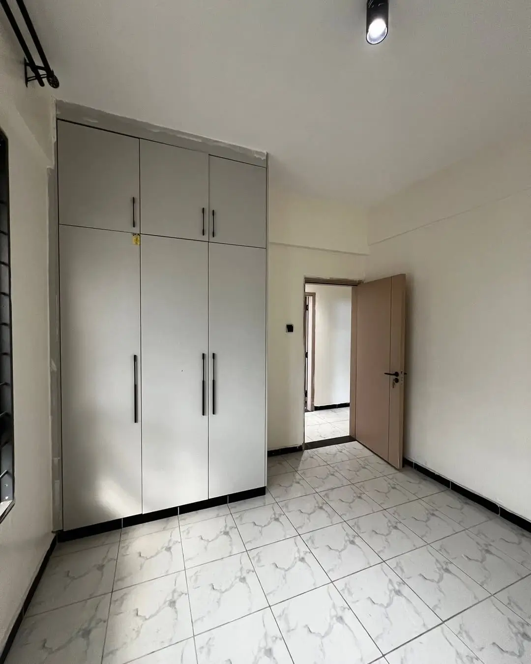 Spacious bedroom with large built-in wardrobes and marble flooring