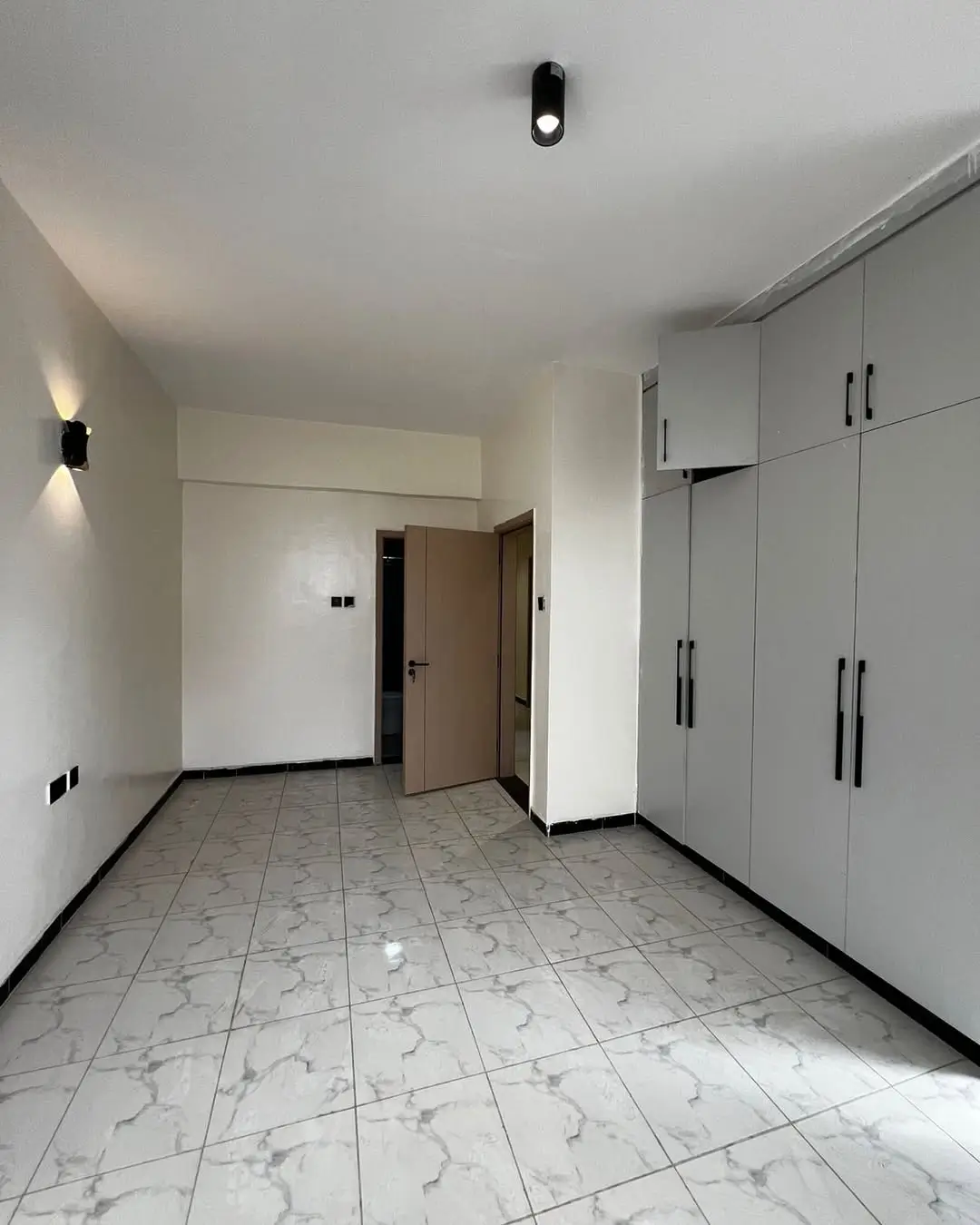 Spacious bedroom with built-in wardrobes and marble flooring