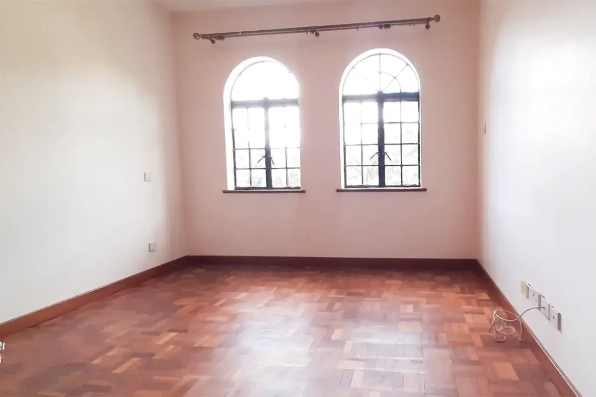 Empty bedroom with arched windows, pink walls, wooden floor