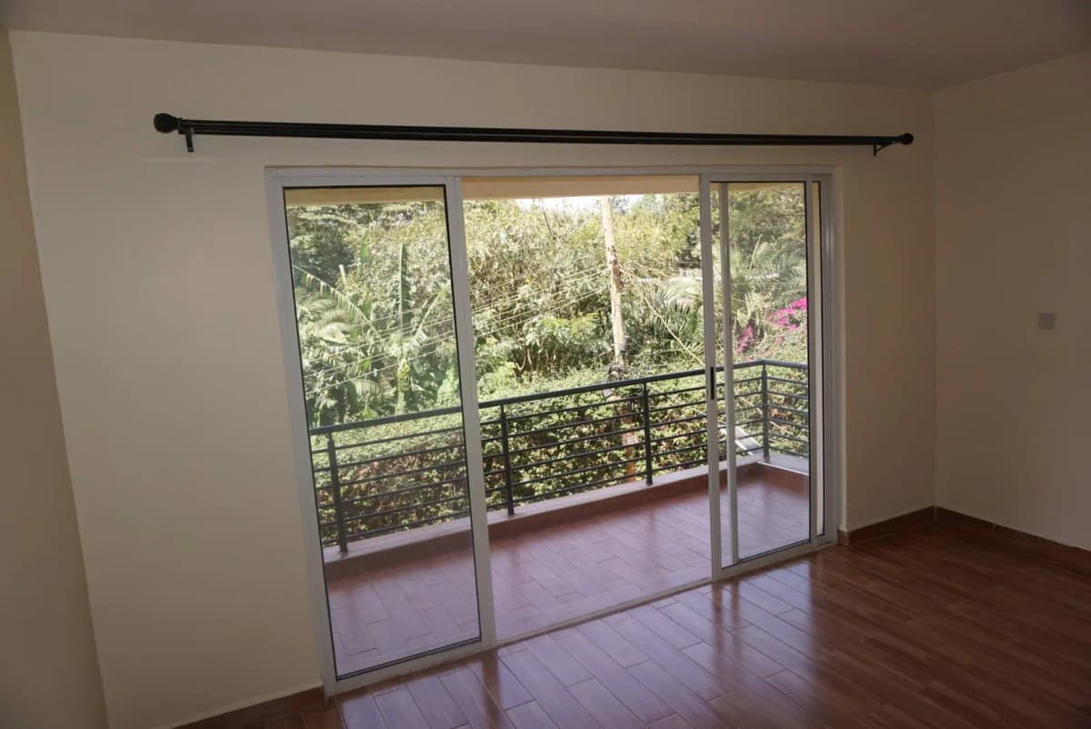 Spacious balcony with glass doors, metal railing, garden views