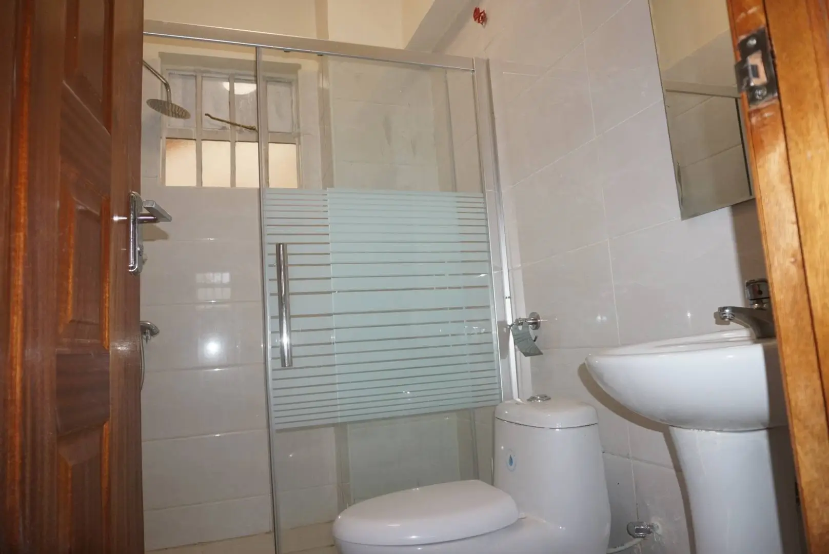 Compact bathroom with toilet, sink, and glass shower enclosure