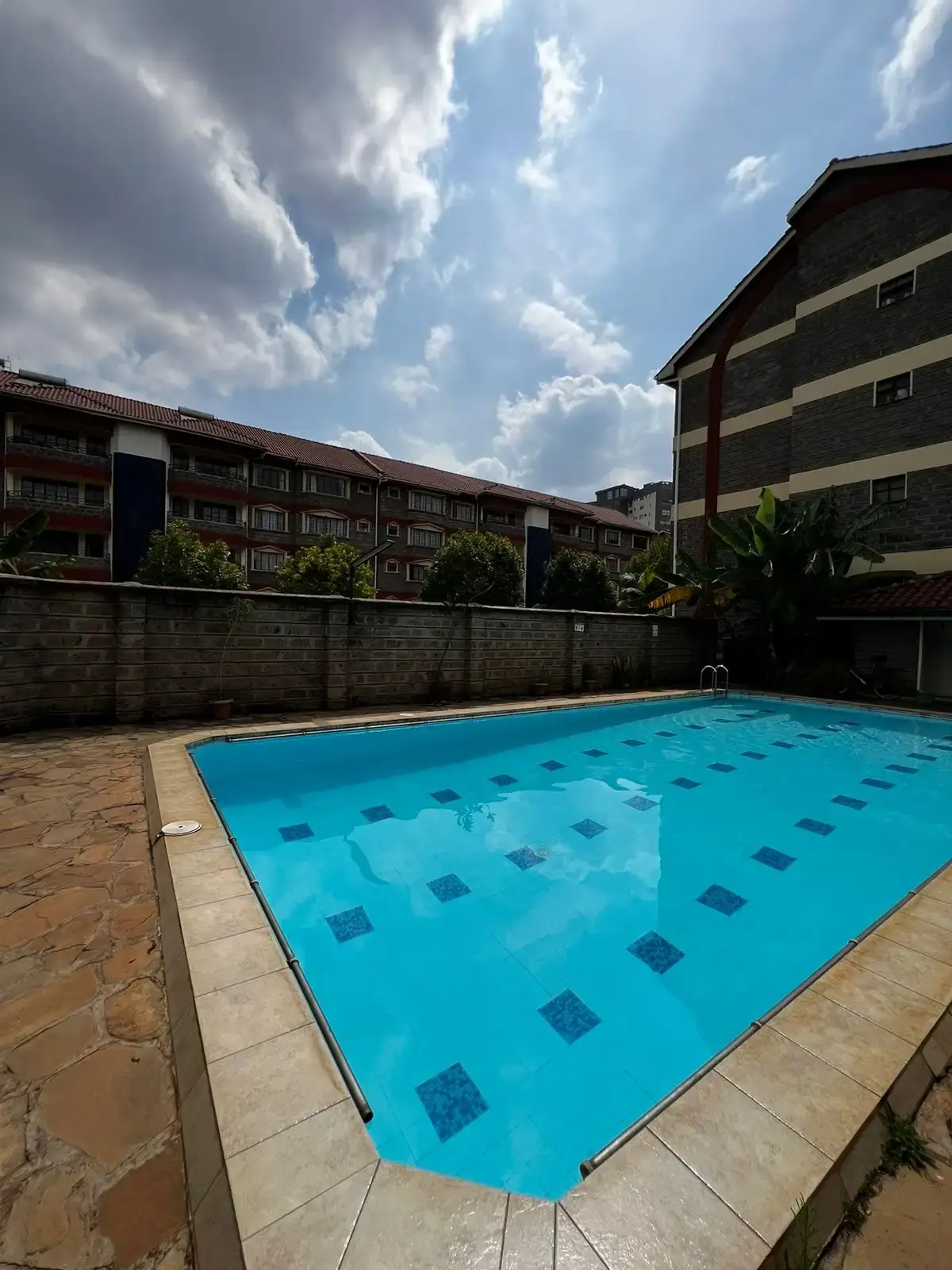 Rectangular swimming pool with diamond pattern tiles, residential compound