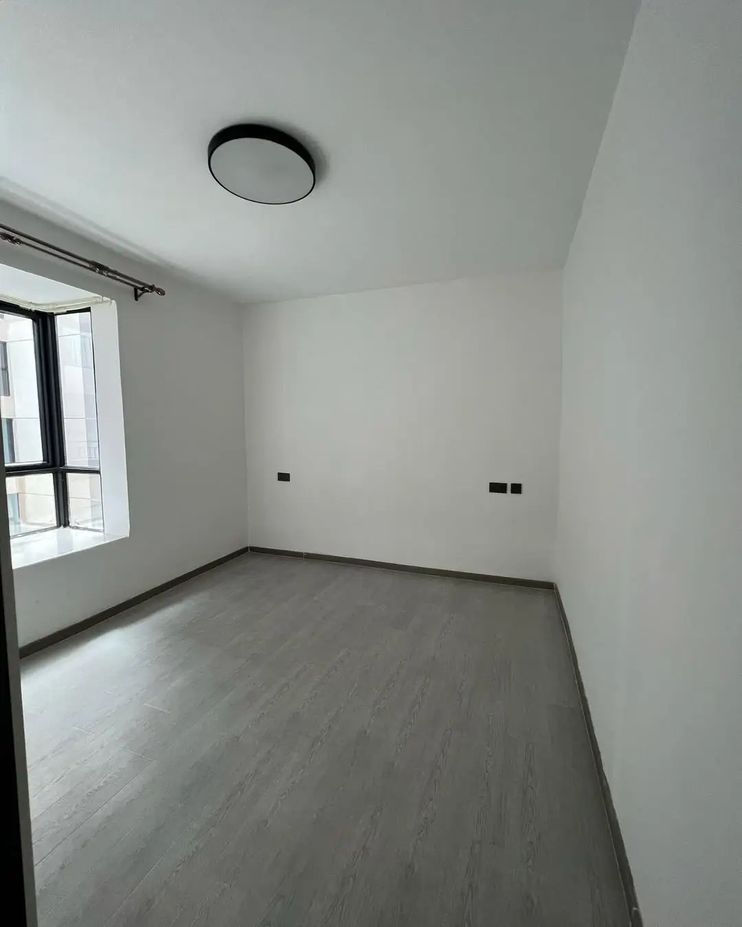 Minimalist bedroom with wooden flooring and window