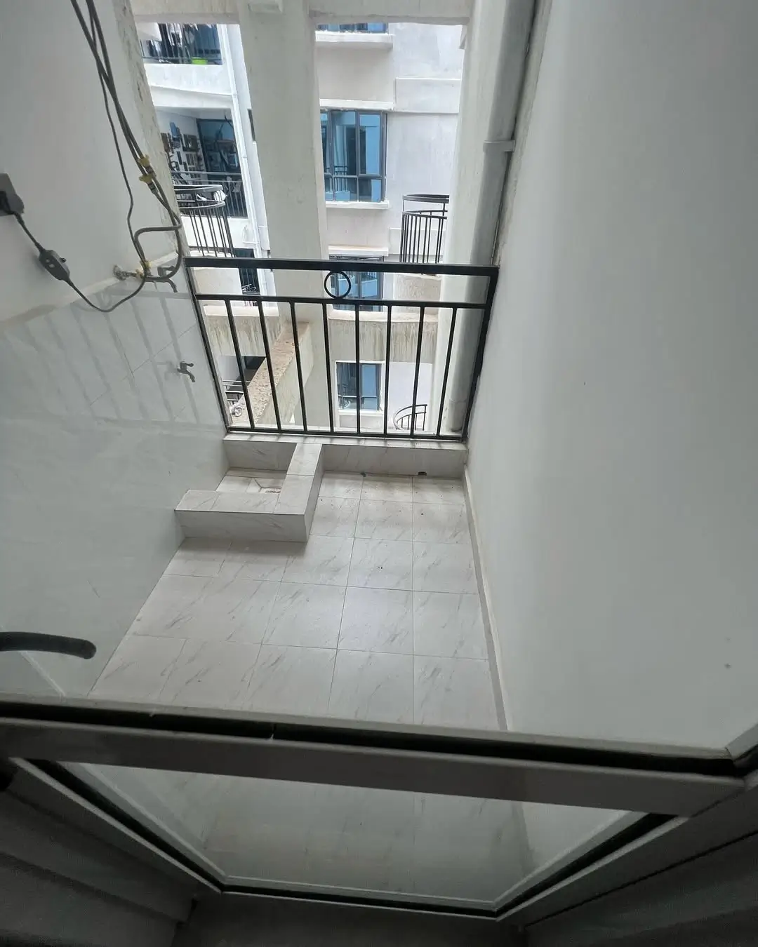 Small balcony with metal railing overlooking residential compound
