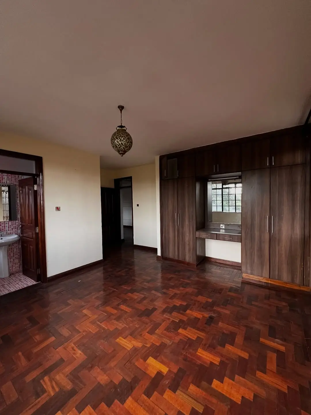 Spacious bedroom with herringbone parquet flooring and pendant light