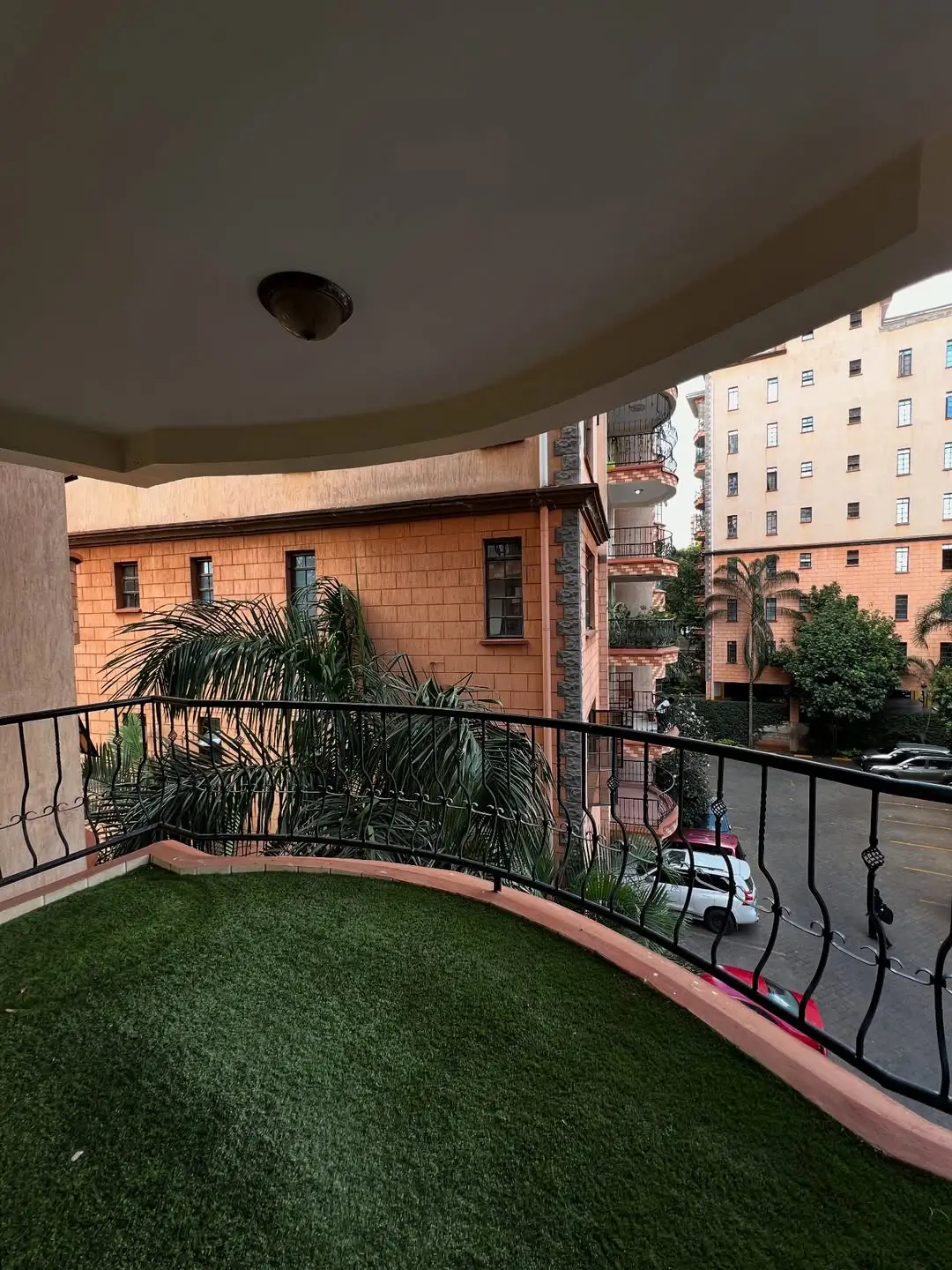 Curved balcony with artificial turf and potted plants overlooking street