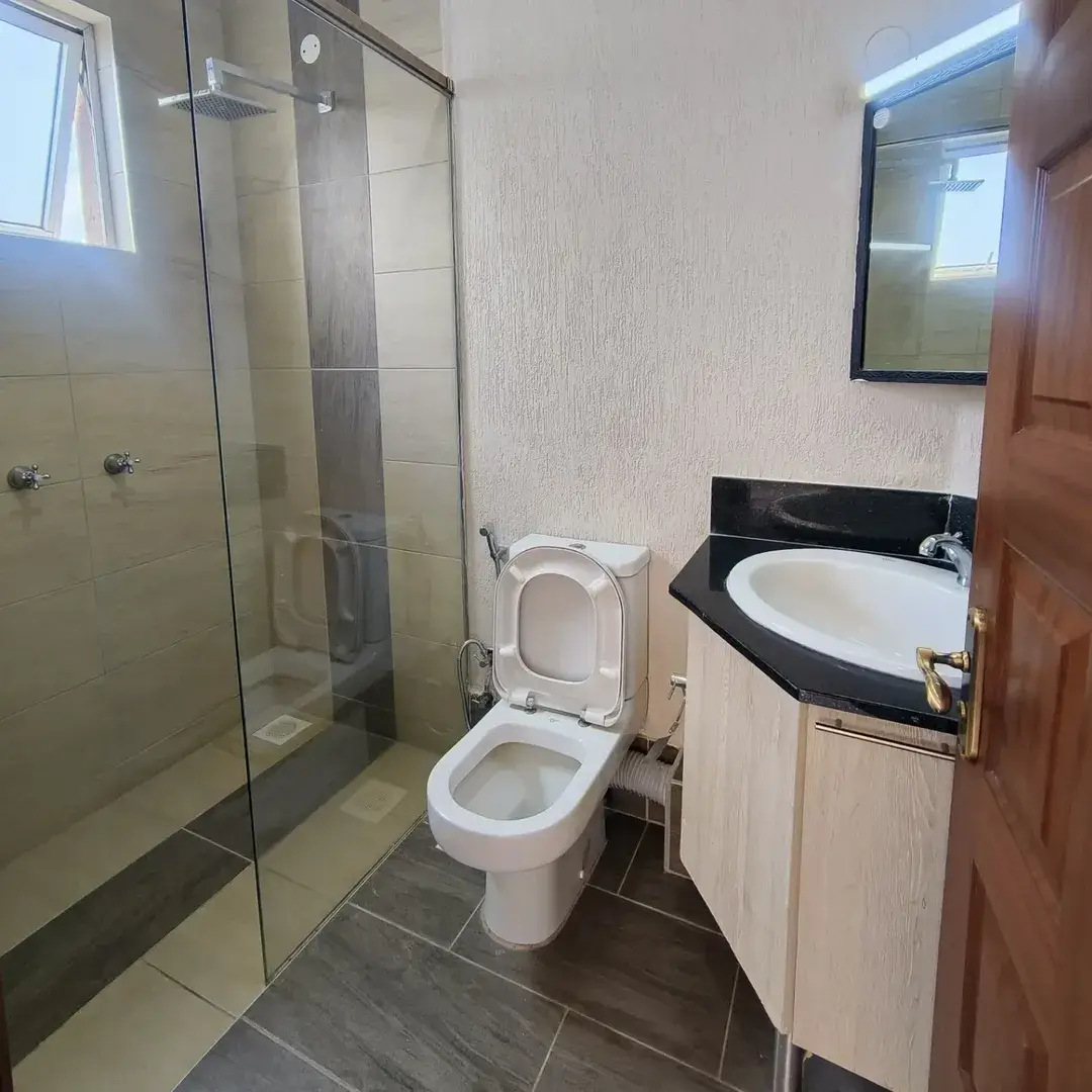 Modern bathroom with toilet, sink, and glass shower enclosure