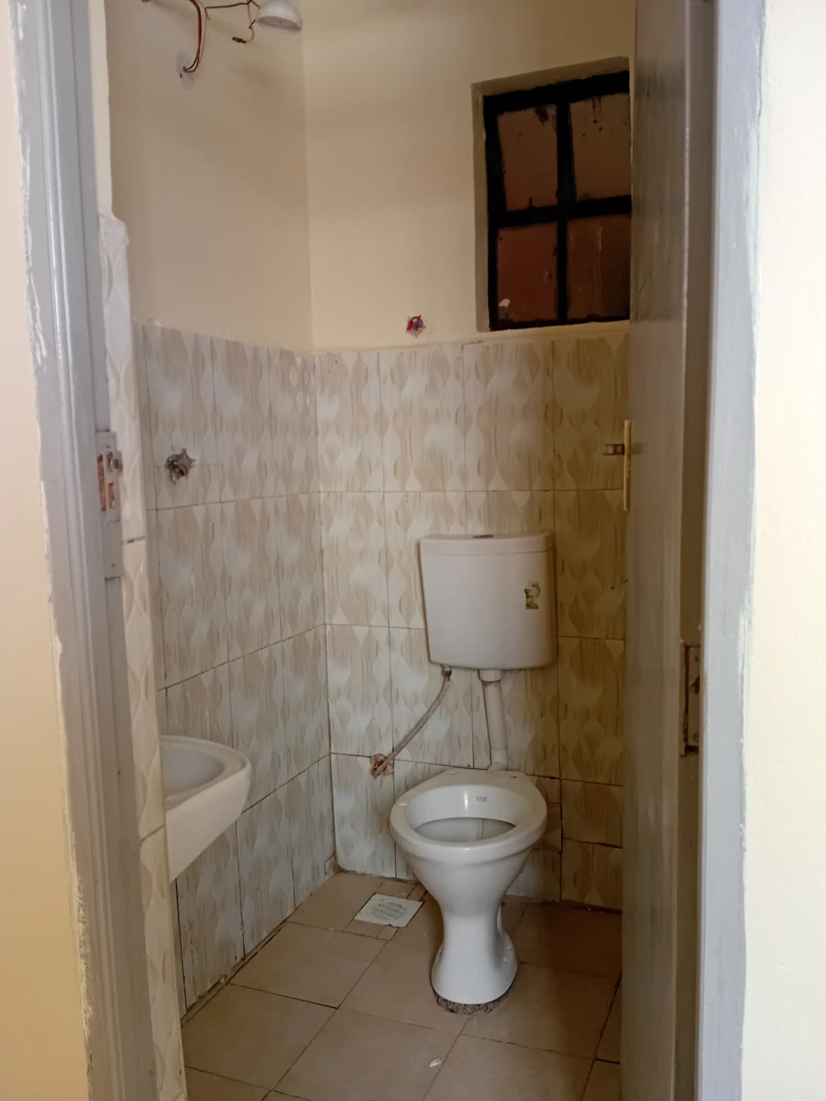 Compact bathroom with toilet, sink, and tiled shower area